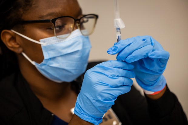 Registered Nurse Toko Nzilani prepares to administer a COVID-19 vaccine at a 9th ward vaccination clinic at the Pullman Community Center in Chicago on Oct. 10, 2024. (Tess Crowley/Chicago Tribune)