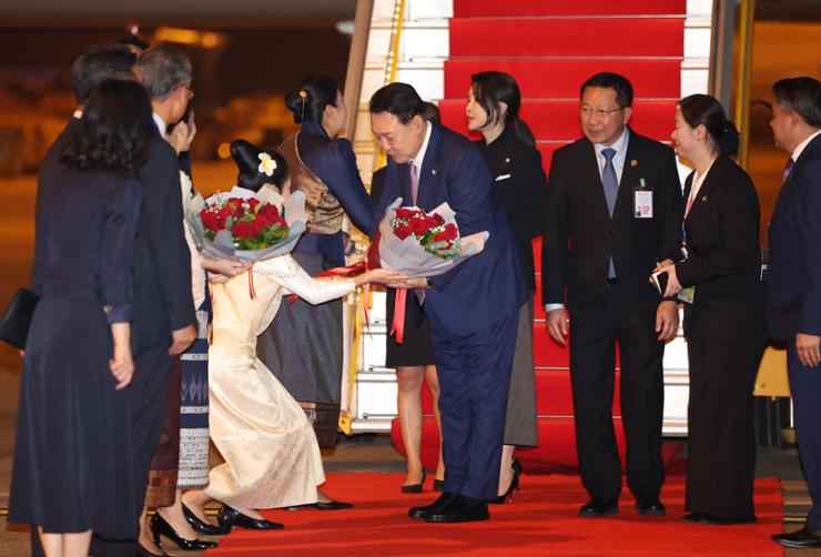 President Yoon Suk Yeol receives a bouquet upon arrival at Wattay International Airport in Vientiane, Laos, Wednesday. Yonhap