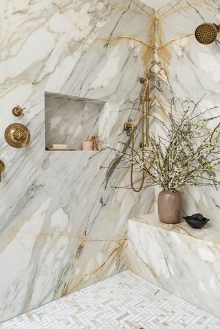 A light marble slab shower with brass fixtures