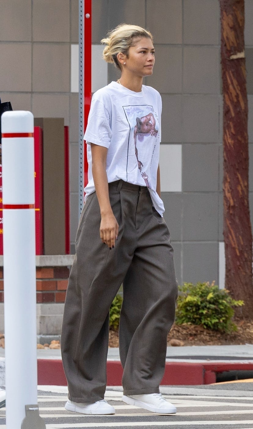 Zendaya wears a graphic T-shirt and trousers.