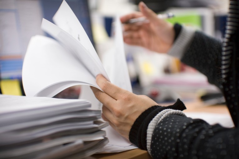 Close-up view of an office worker checking paper documents at a desk